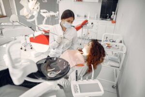 Dentista atendendo uma mulher em seu consultório.